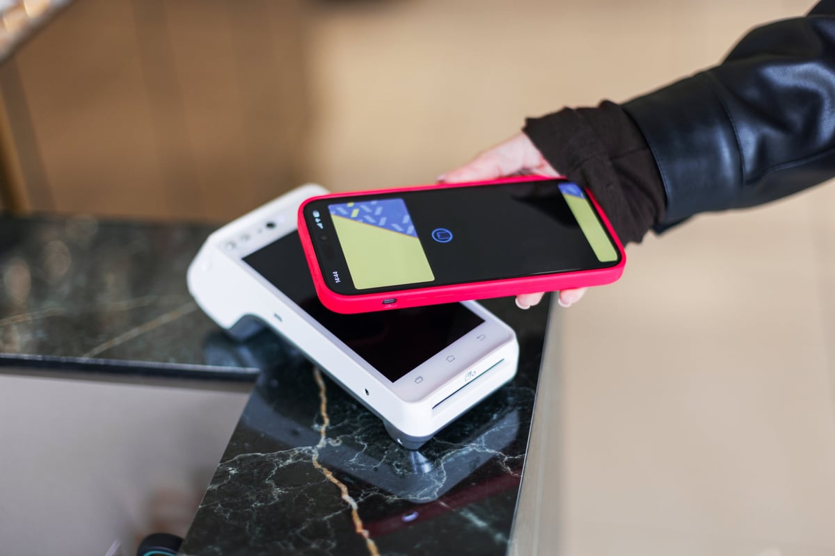 Hand using a smartphone to pay at a modern point-of-sale terminal